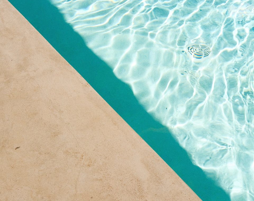 Eau turquoise au bord d'une piscine, le long d'une margelle en pierre claire
